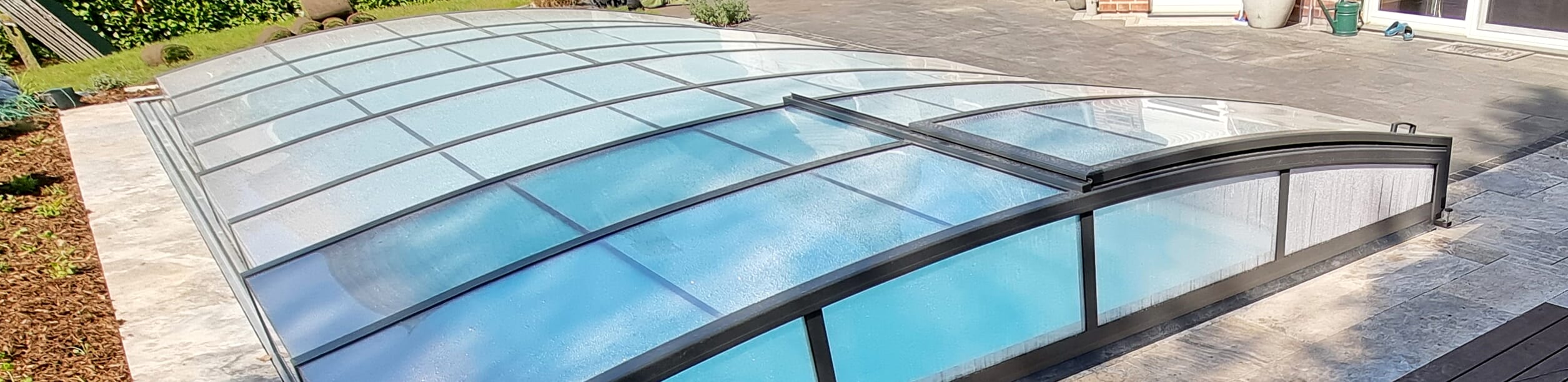 Teleskopüberdachung mit geschlossenen Schiebeelementen, die das Poolbecken vollständig abdeckt.